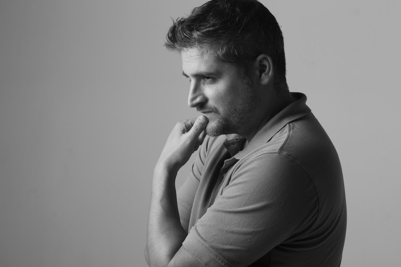 Black and white profile of a man with hand on chin, looking thoughtful, against a plain background.